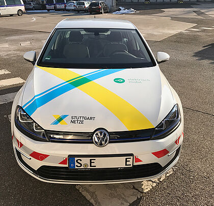 Von vorne gezeigter VW-Polo der EnBW-Fahrzeugflotte auf einem Parkplatz mit bedruckter Motorhaube.