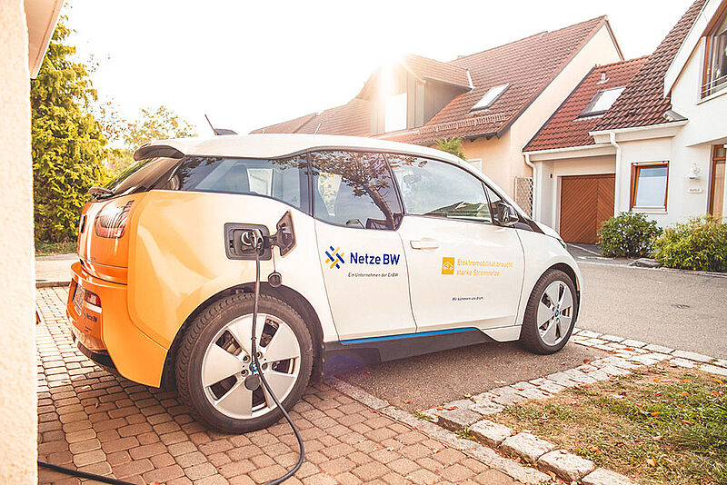 Elektroauto der GmbH Netze BW beim Tanken in einem Familienhaus Viertel bei Sonnenschein.