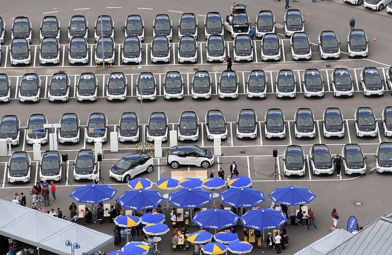 Großer Parkplatz aus der Vogelperspektive vollgestellt mit BMW i3's und blauen Schirmen.