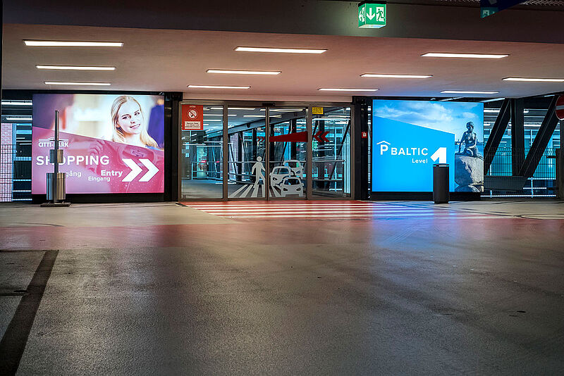 Wegeleitsystemische Beschilderung bei einem Shoppingcenter Eingang vom Parkplatz aus.