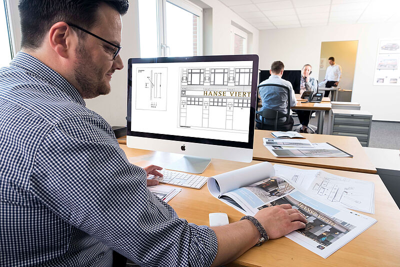 Mitarbeiter beim Erarbeiten eines Konzepts am iMac im Büro.