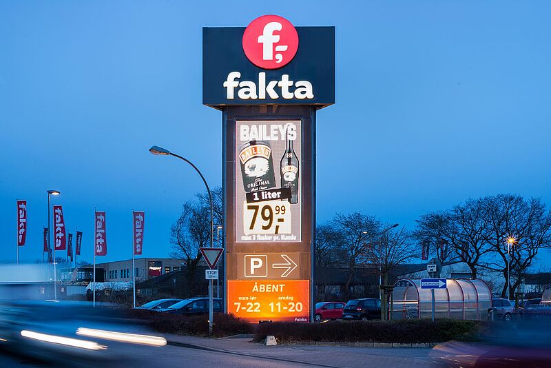 Digita Signage mit einem großen "fakta" Logo Schild, Baileys Werbung und Parkplatzhinweis.