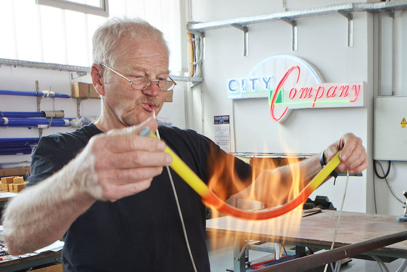 Facharbeiter beim Herstellen einer Neonroehre in individueller Form in einer Werkstatt.